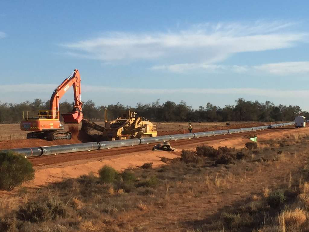 Workers using machinery to create space under ground for the pipeline. 