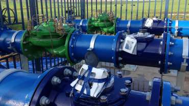 three blue water pressure meters next to each other in front of a fence